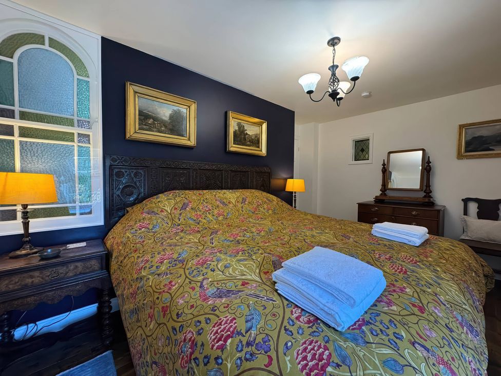 A bedroom with a bed and side table at St. James Cottage in Liskeard