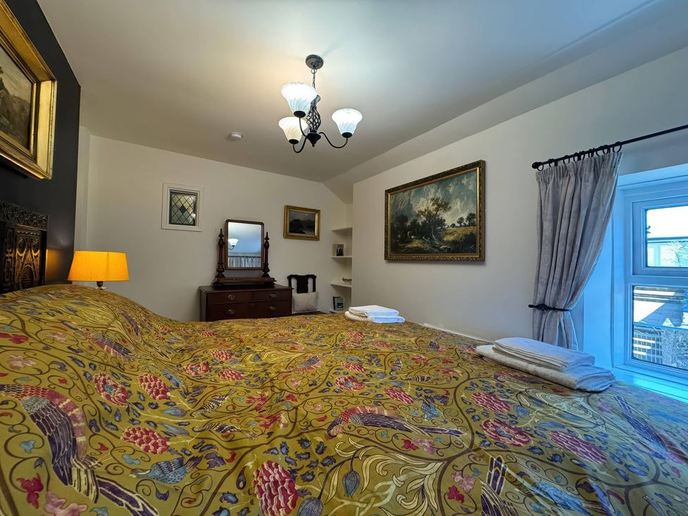 A bedroom with a bed and mirror at St. James Cottage in Liskeard