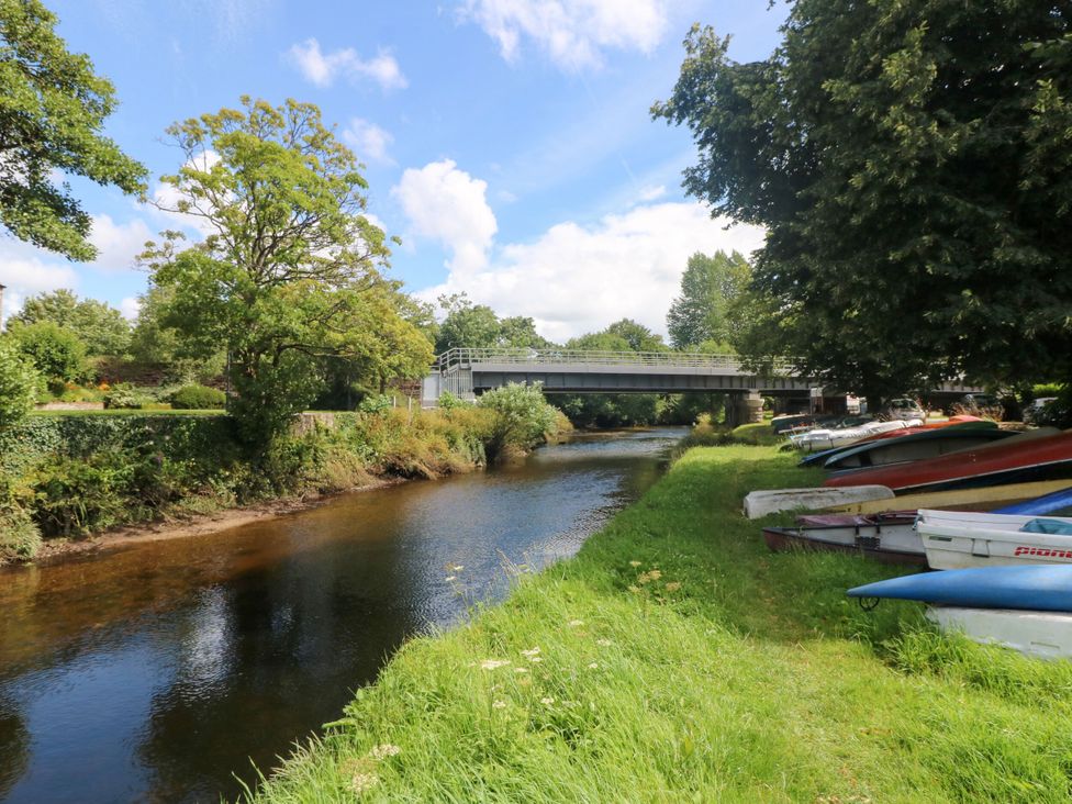 A river with a bridge and boats along the bank at St. James Cottage in St Cleer
