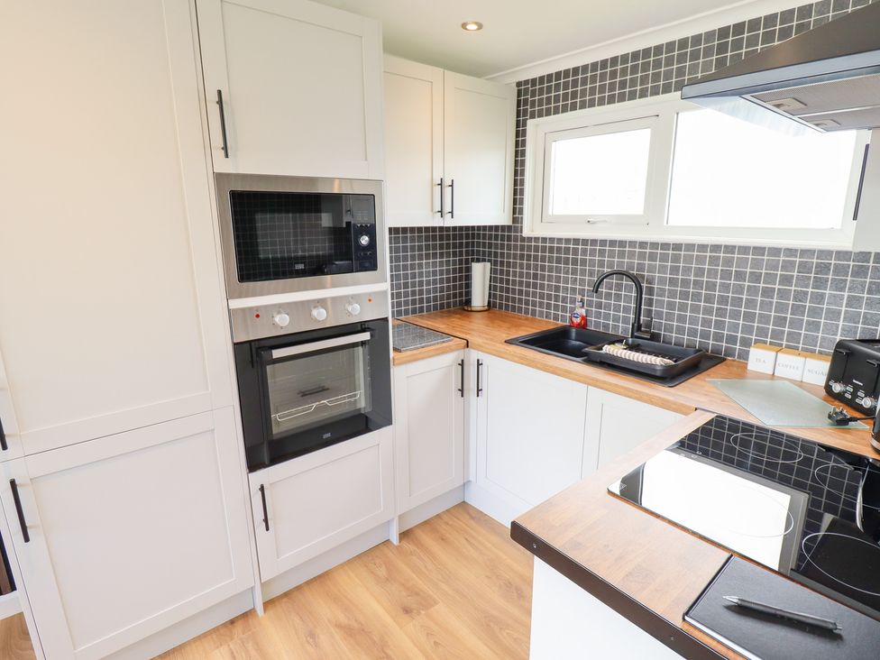 A kitchen with oven and microwave at 66 Cherry Park in Skegness
