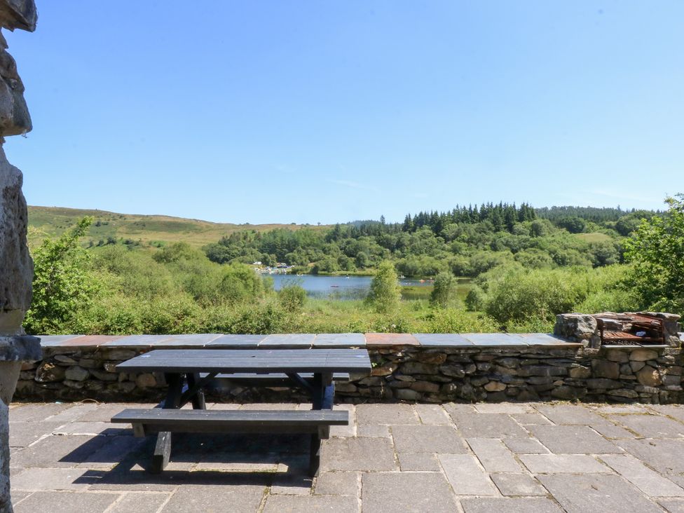 A table with benches overlooking a lake and trees at Ty Newydd