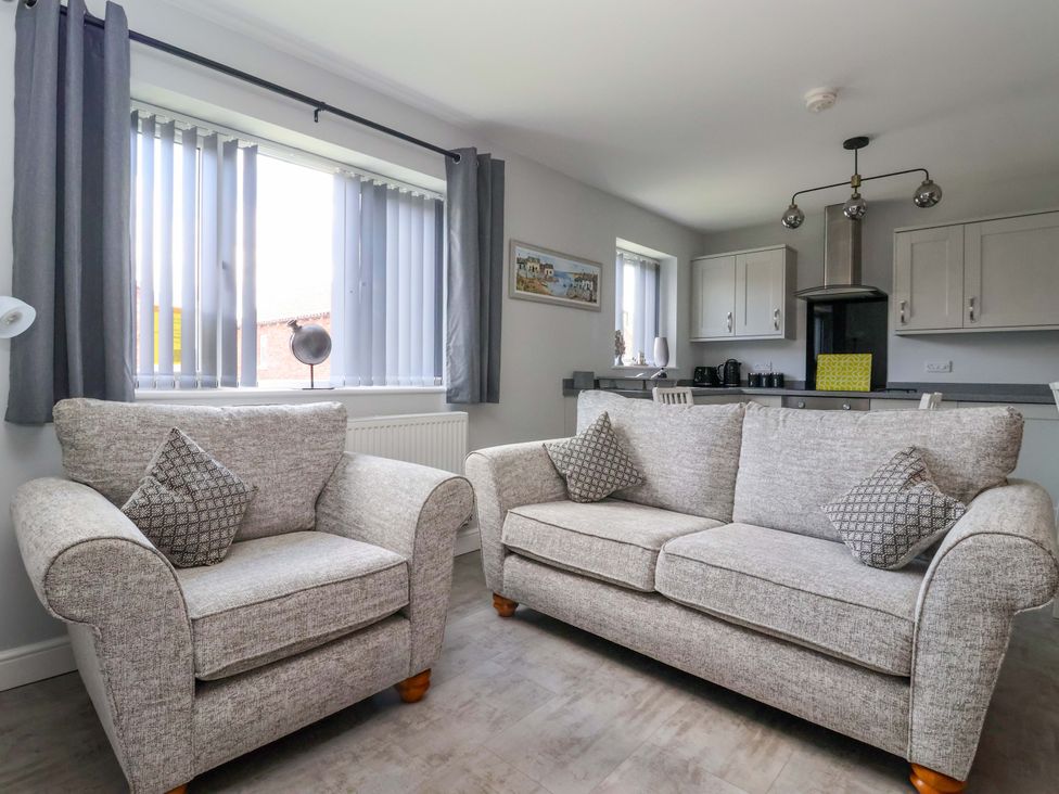 A living room with two sofas and a kitchen area visible at Dan’s Holiday Cottage in Driffield
