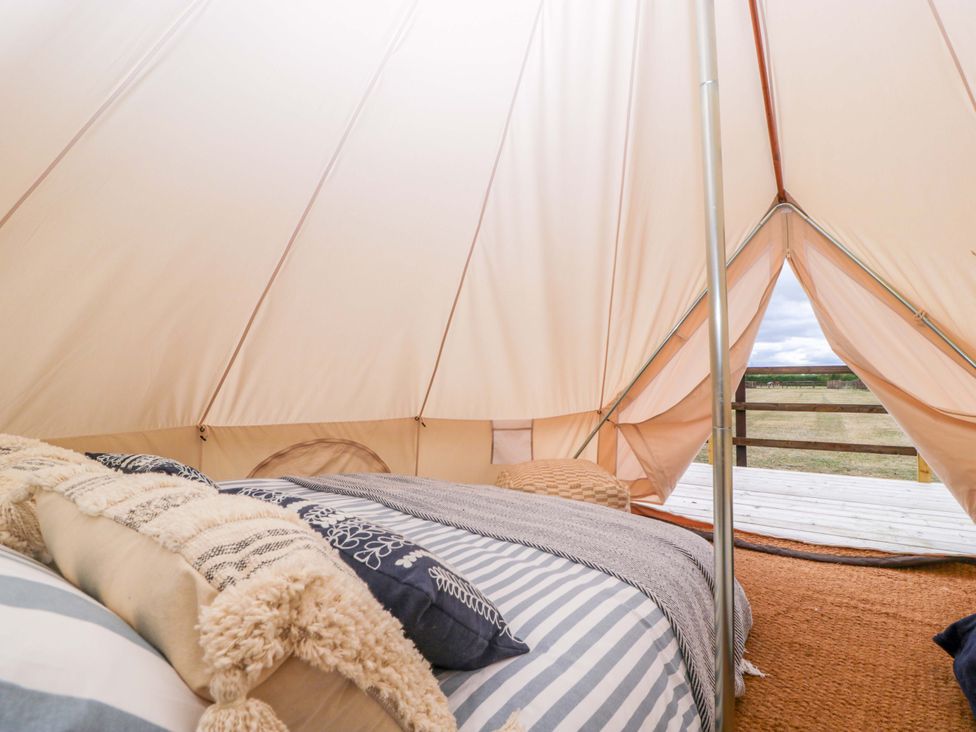 A glamping tent with a bed and pillows at Bell 2 in Shades Farm near Malmesbury
