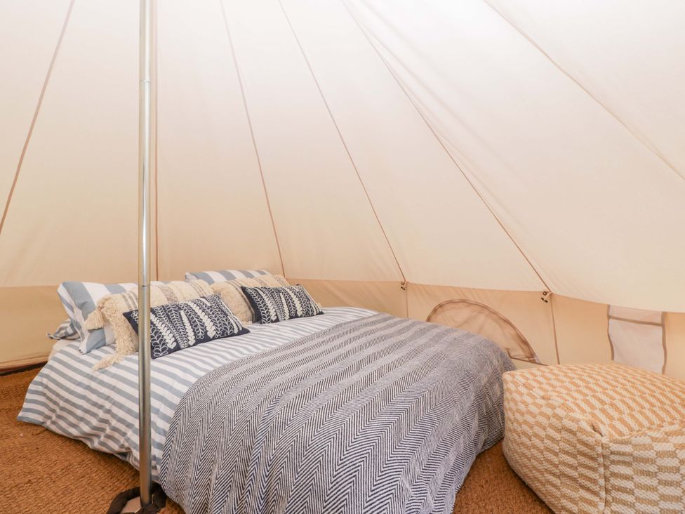 A tent interior with a bed and pillows at Bell 2, Shades Farm near Malmesbury