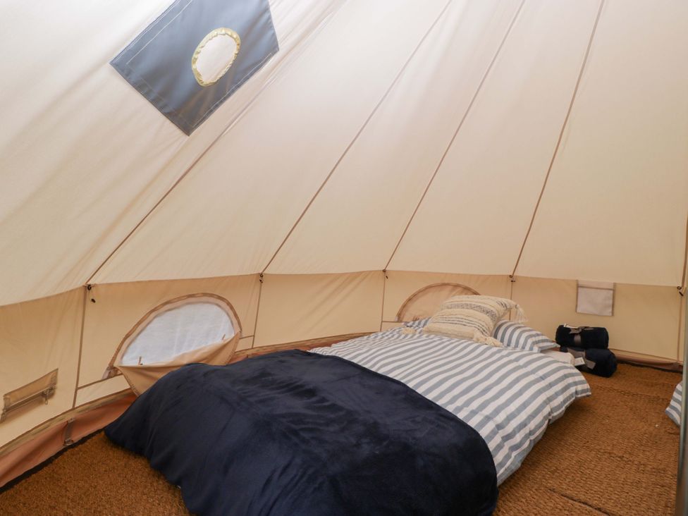 A bedroom with bedding and pillows inside a tent at Bell 2 Shades Farm near Malmesbury