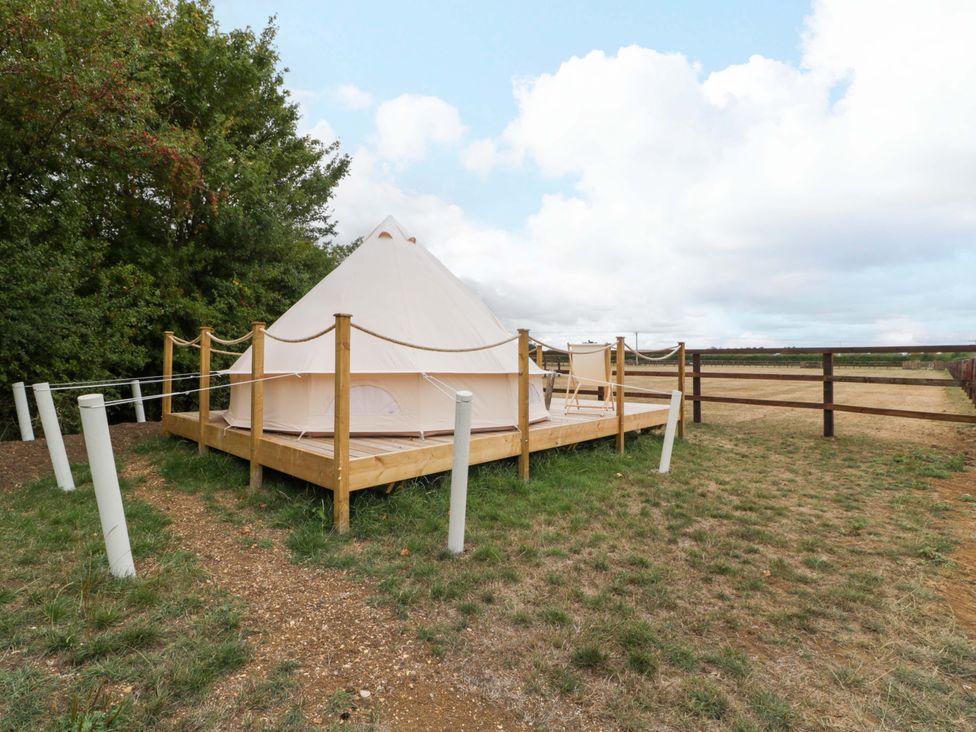A tent on a wooden deck surrounded by grass at Bell 2 near Shades Farm near Malmesbury