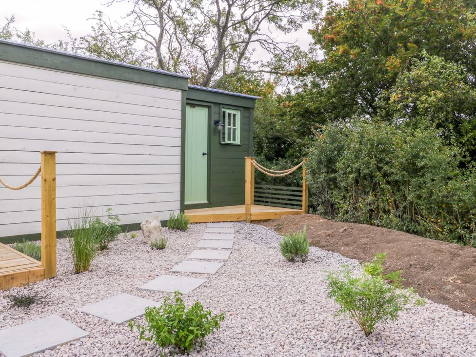An outdoor area with a walkway and a green door at Bell 2, Shades Farm near Malmesbury