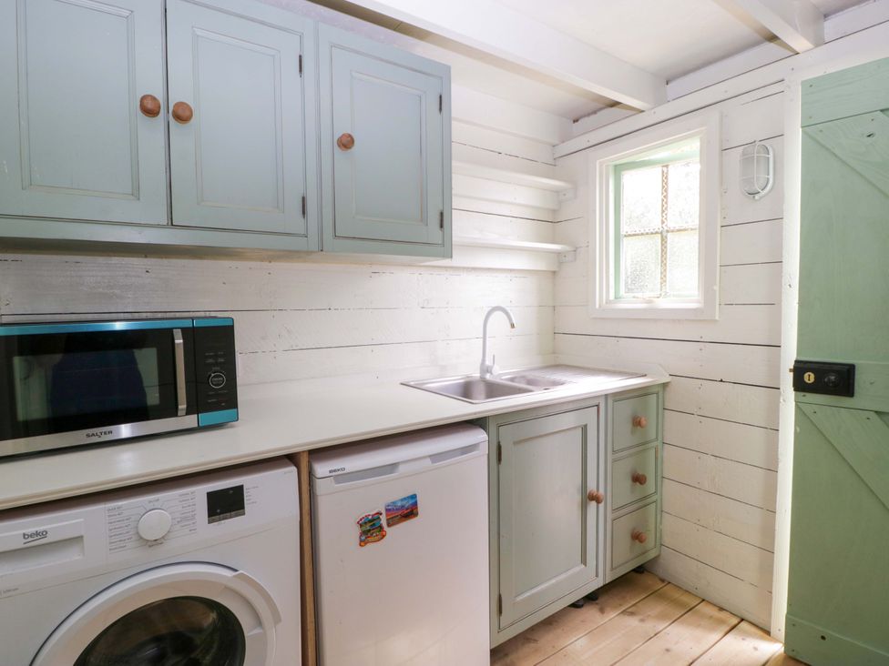 A kitchen with a washing machine, fridge, microwave, and sink at Bell 2 Shades Farm near Malmesbury