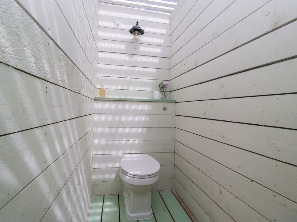 A bathroom with a toilet and a shelf at Bell 2, Shades Farm near Malmesbury