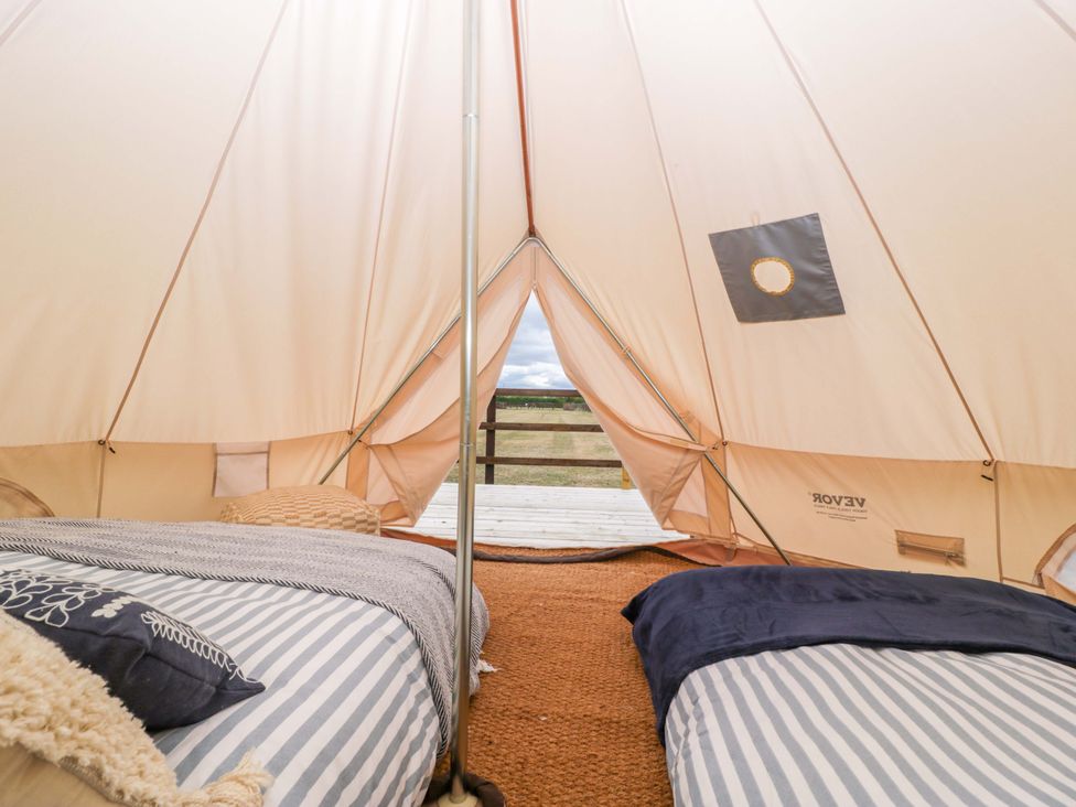 A bedroom with beds inside a tent at Bell 3 Shades Farm near Malmesbury