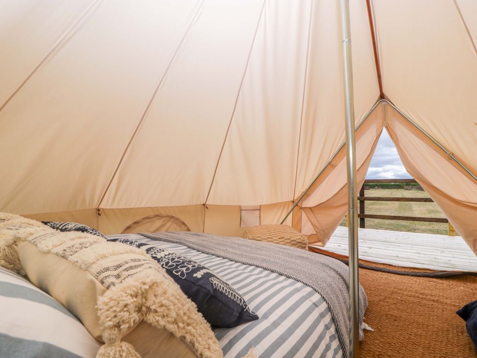 A tent interior with a bed and pillows at Bell 3 Shades Farm near Malmesbury