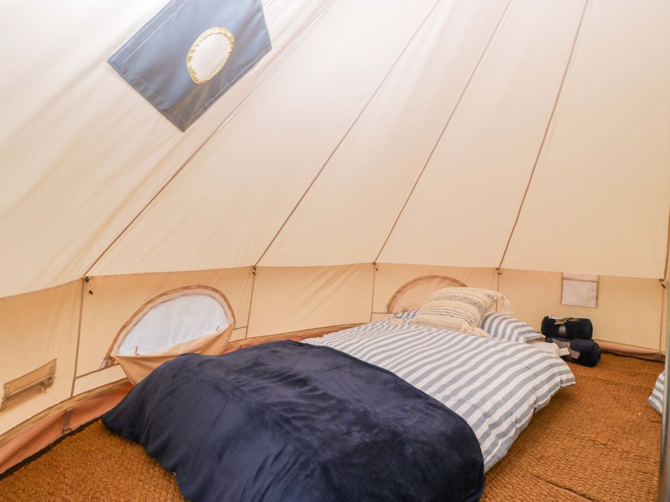 A tent with a bed and bedding at Bell 3 Shades Farm near Malmesbury
