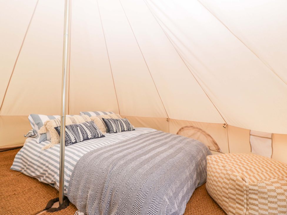 A bedroom with a bed and cushions at Bell 3 Shades Farm near Malmesbury