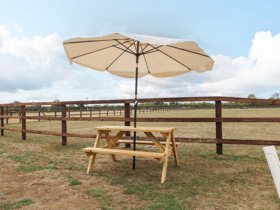 A wooden table with benches and an umbrella outdoors at Bell 3, Shades Farm near Malmesbury