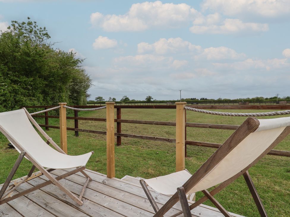 A deck area with chairs overlooking a field at Bell 3 Shades Farm near Minety