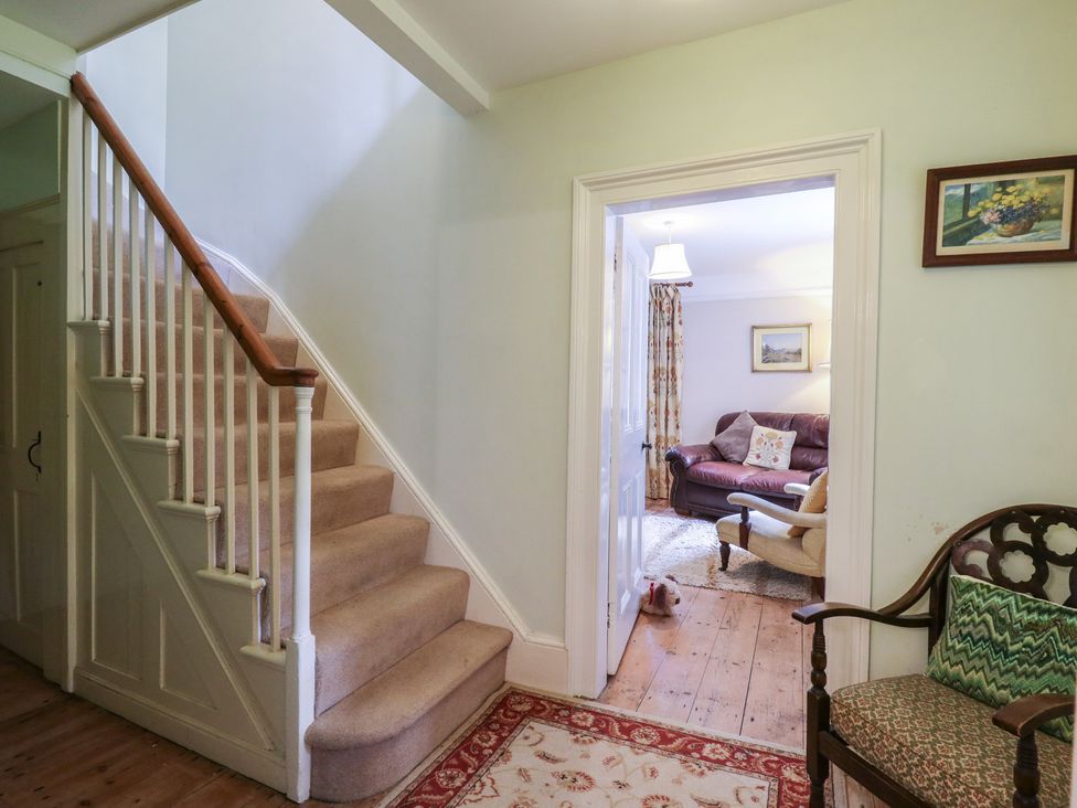 A hallway with a staircase and a doorway to a living room at Curry Farm