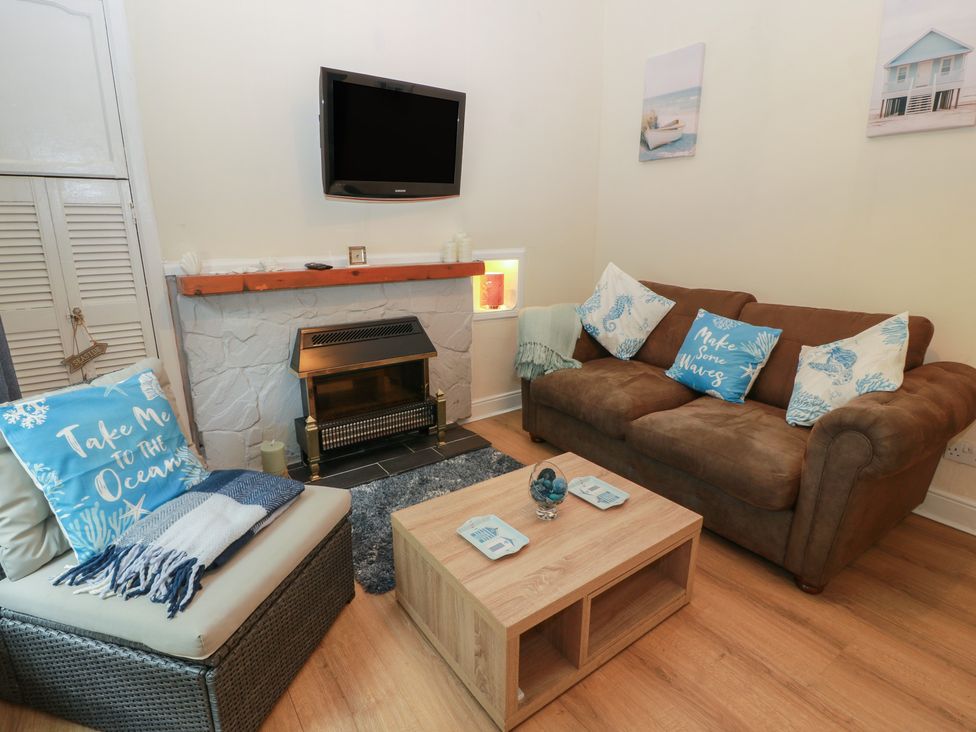 A living room with a sofa, armchair, television and coffee table at 6 George Street Isle of Cumbrae