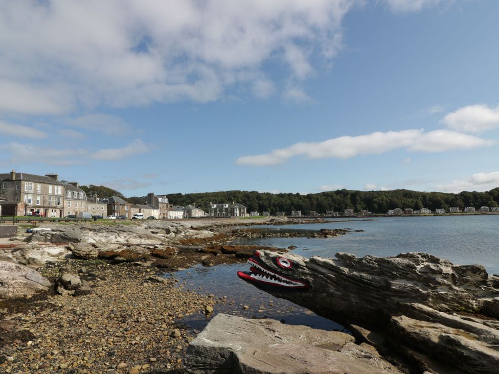 A shoreline with rocky beach and buildings along the water at 6 George Street Isle of Cumbrae