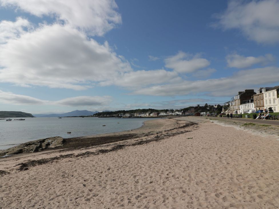 A beach view with buildings and pathway at 6 George Street in Isle of Cumbrae