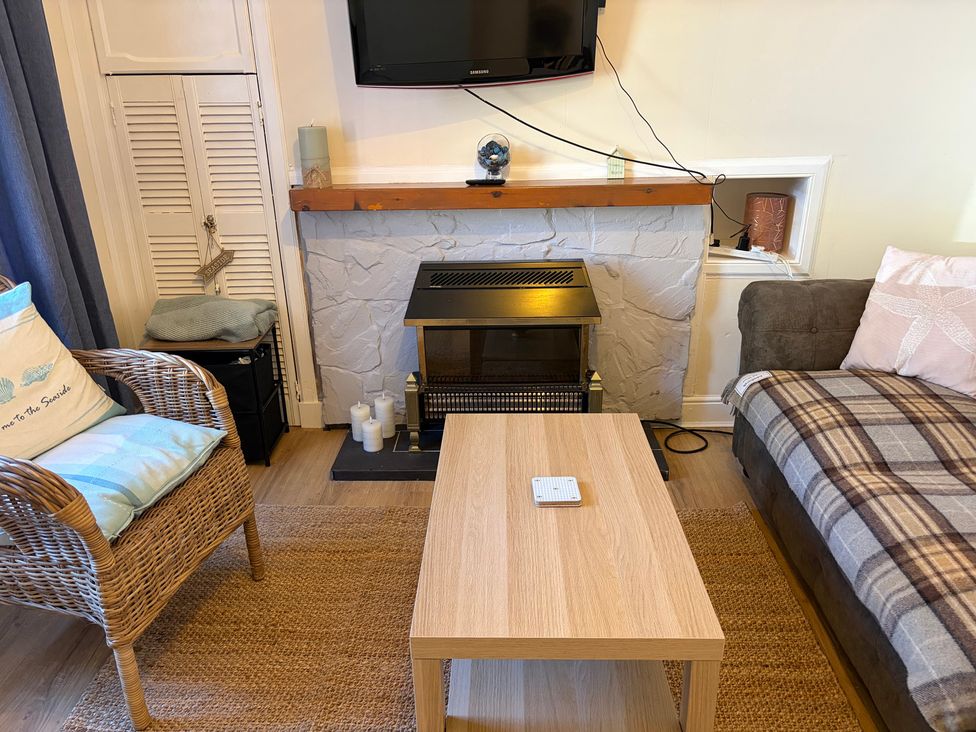 A living room with a TV and fireplace at Cosy In Millport