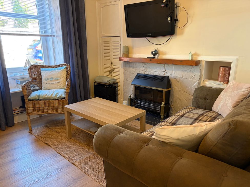 A living room with a chair couch and coffee table at Cosy In Millport