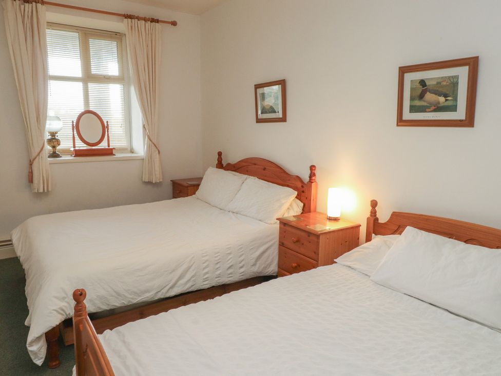 A bedroom with two beds and a lamp at King Arthur Suite in Trearddur Bay