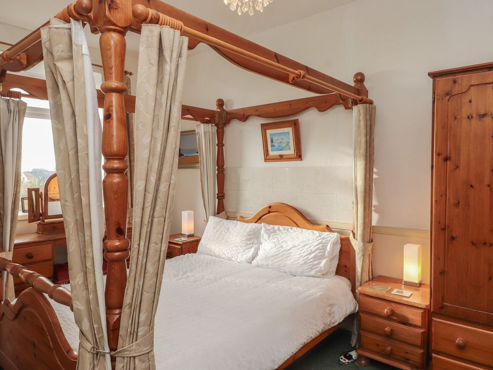 A bedroom with a four-poster bed and bedside tables at King Arthur Suite Trearddur Bay