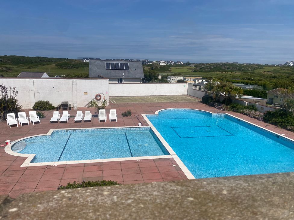 An outdoor pool area with lounge chairs at King Arthur Suite Trearddur Bay