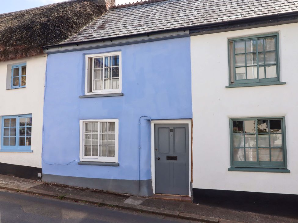 An exterior view of a house with a blue wall and gray door at Carpenters Cottage in Okehampton