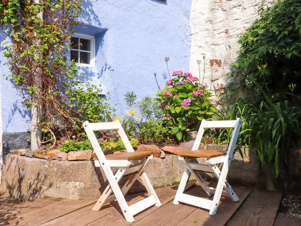 Two chairs in a garden near flowers at Carpenters Cottage in Okehampton