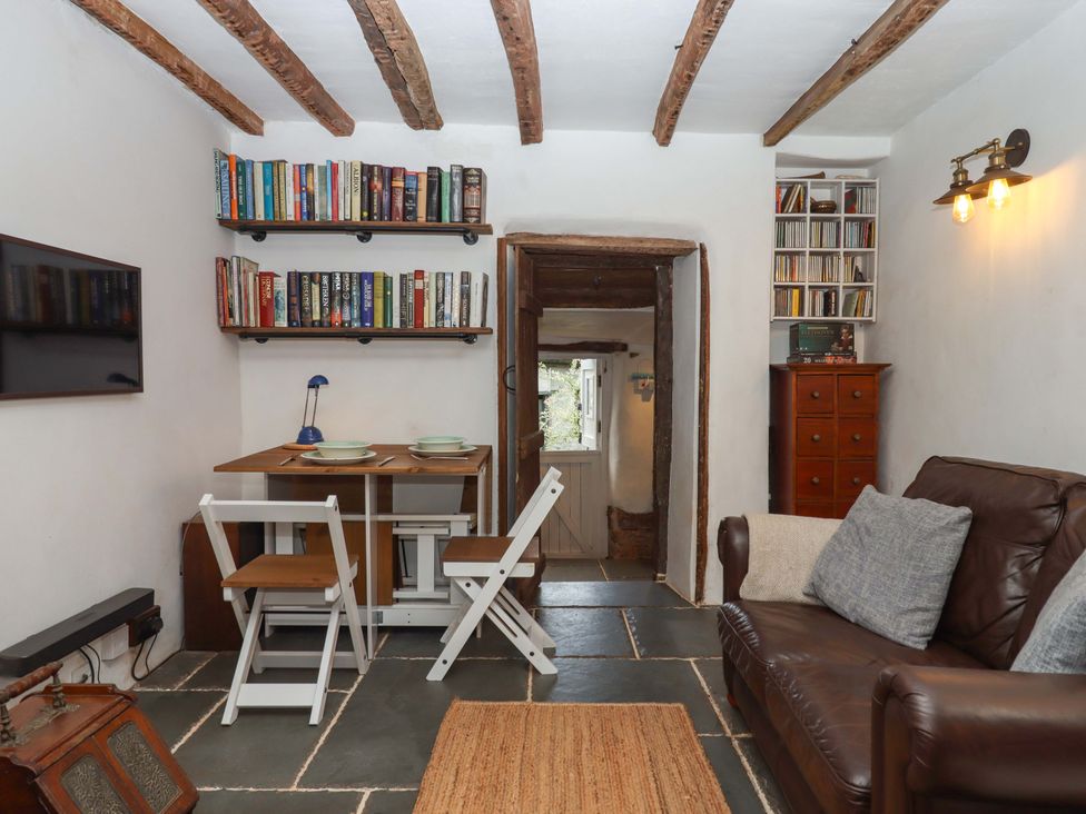 A living room with bookshelves and a table at Carpenters Cottage Okehampton
