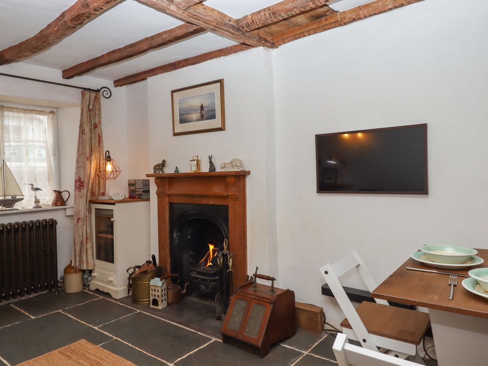 A living room with a fireplace and dining area at Carpenters Cottage Okehampton