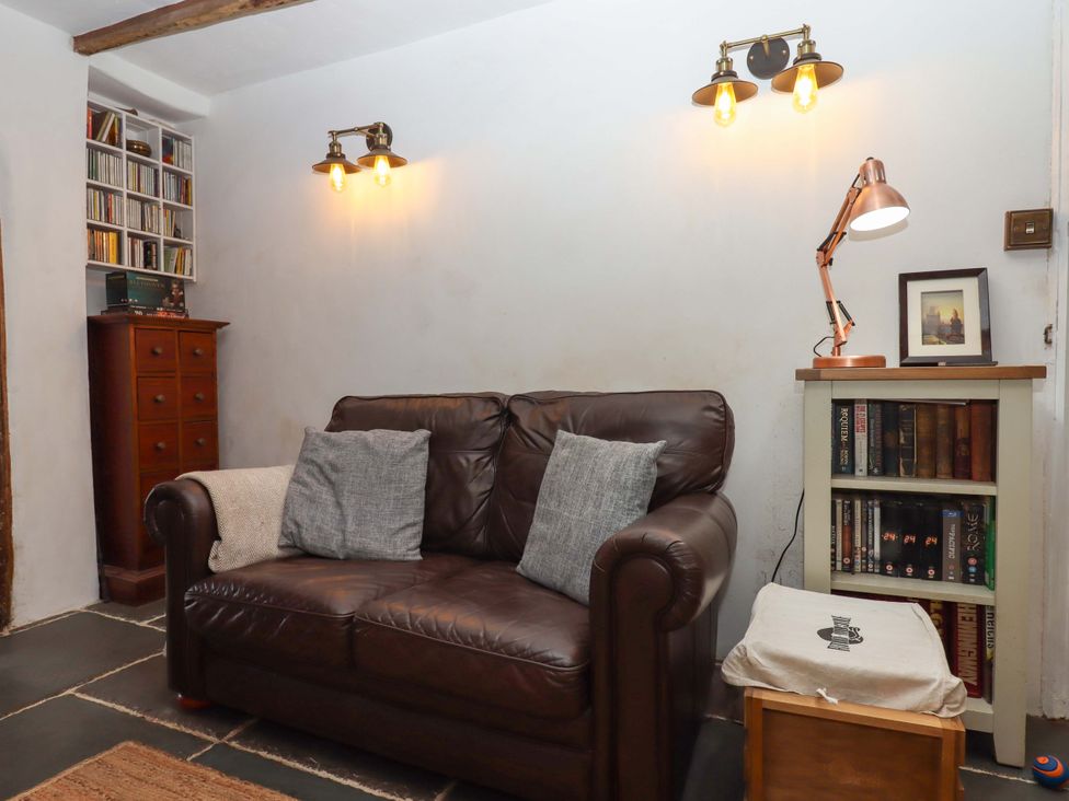 A living room with a sofa and bookshelves at Carpenters Cottage Okehampton