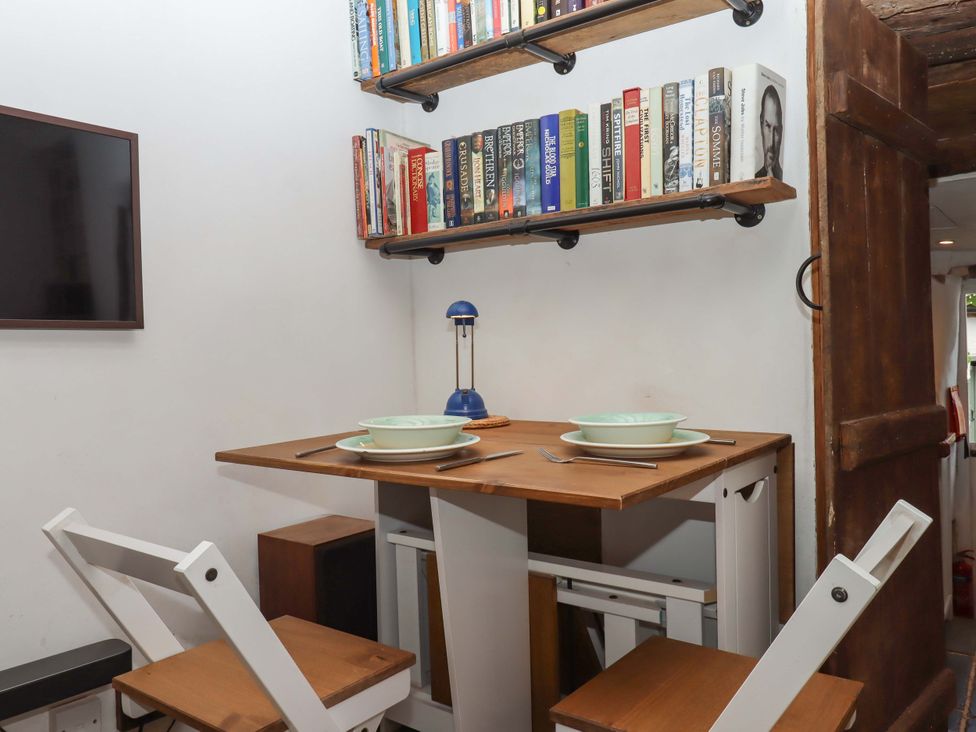 A dining area with a table, chairs and a bookshelf at Carpenters Cottage in Okehampton