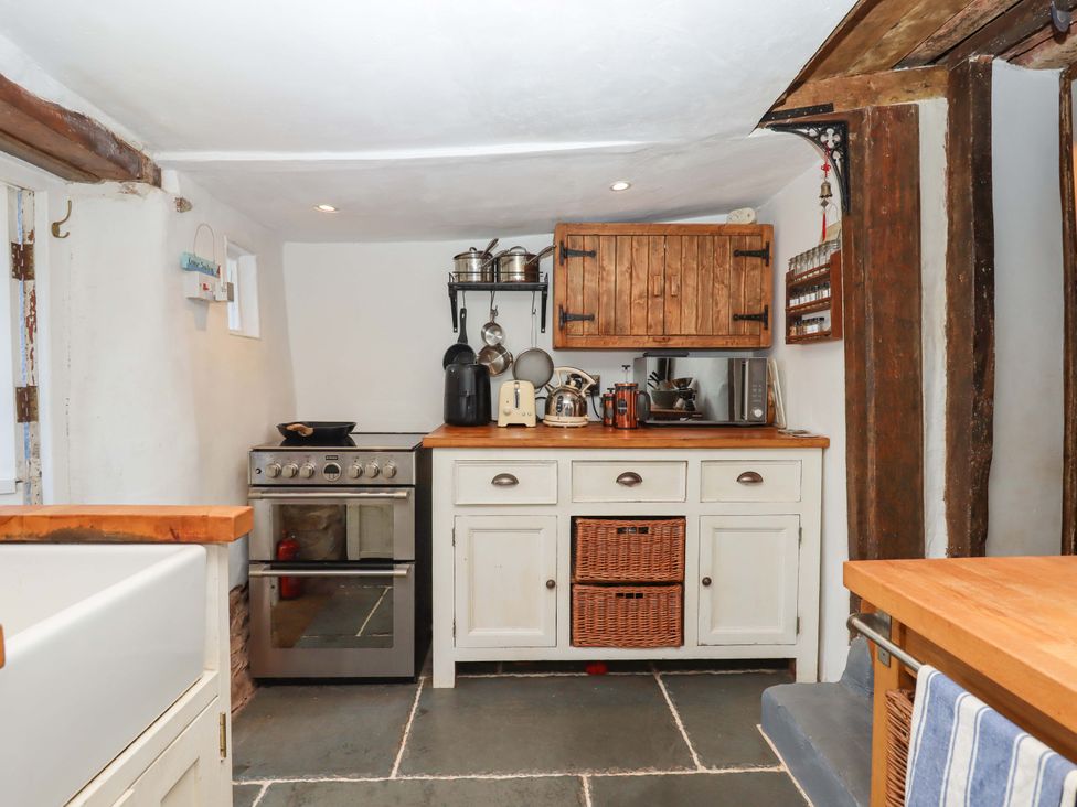 A kitchen with stove and wooden cabinets at Carpenters Cottage in Okehampton