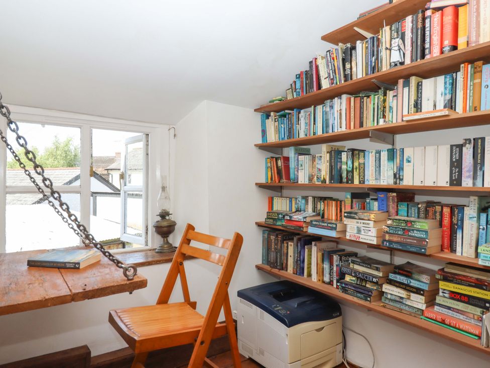 A study with bookshelves and a window at Carpenters Cottage in Okehampton