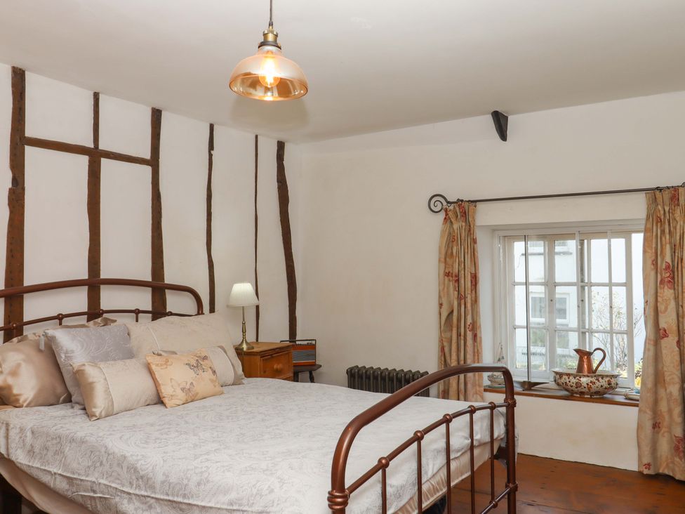 A bedroom with a bed and window at Carpenters Cottage Okehampton