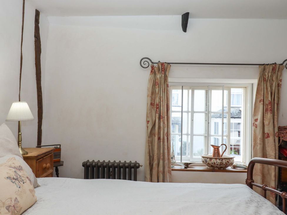 A bedroom with a bed and a window at Carpenters Cottage Okehampton