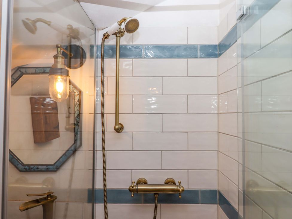 A shower area featuring a showerhead and a light fixture at Carpenters Cottage in Okehampton