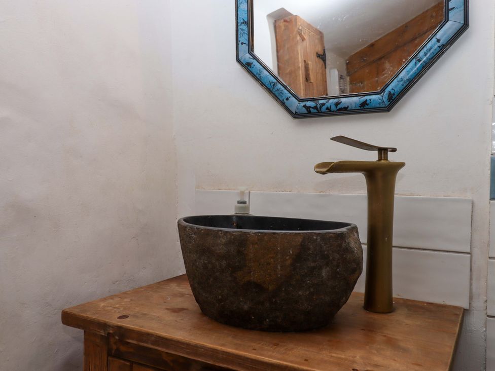 A sink with a faucet and a mirror at Carpenters Cottage Okehampton