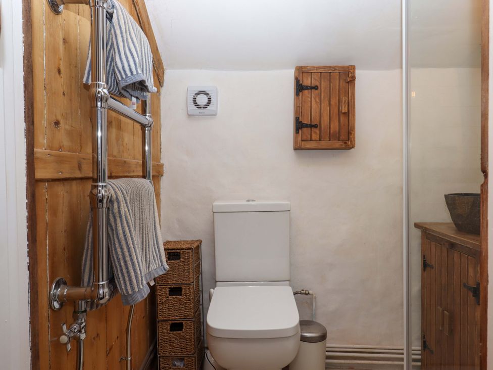 A bathroom with a toilet, towel rail, and wooden storage at Carpenters Cottage Okehampton
