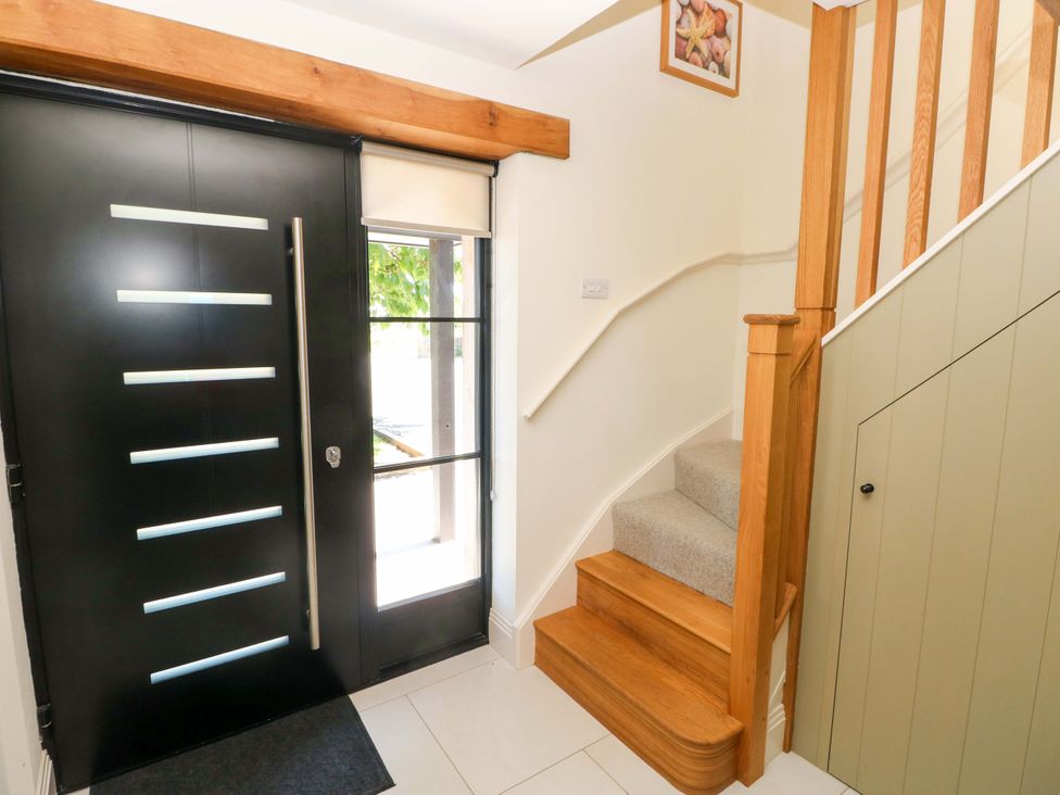 A hallway with a front door and staircase at Just A Cottage St Florence