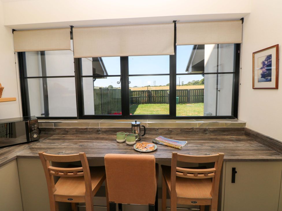 A kitchen with a counter, microwave, kettle, and two chairs at Just A Cottage St Florence