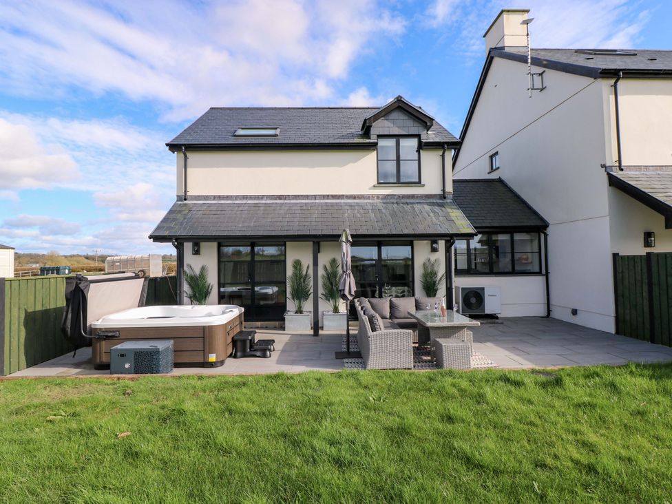 An outdoor area with a hot tub and patio furniture at Just A Cottage, St Florence