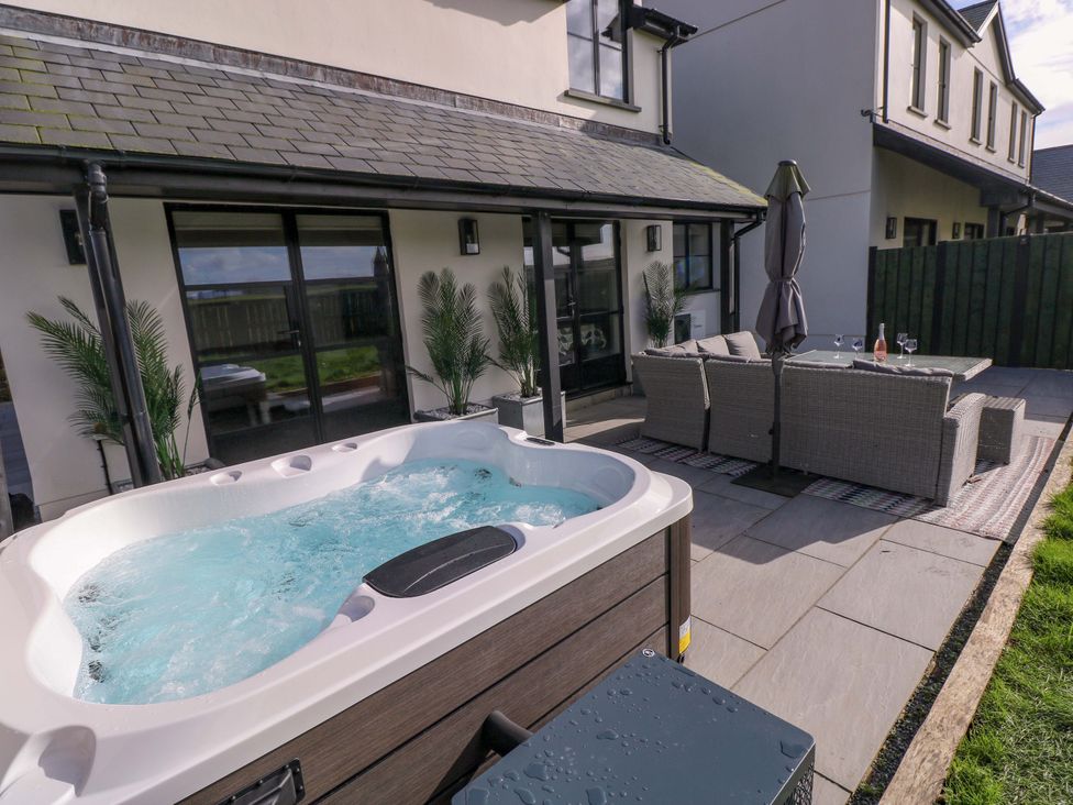An outdoor patio with a hot tub and seating area at Just A Cottage in St Florence
