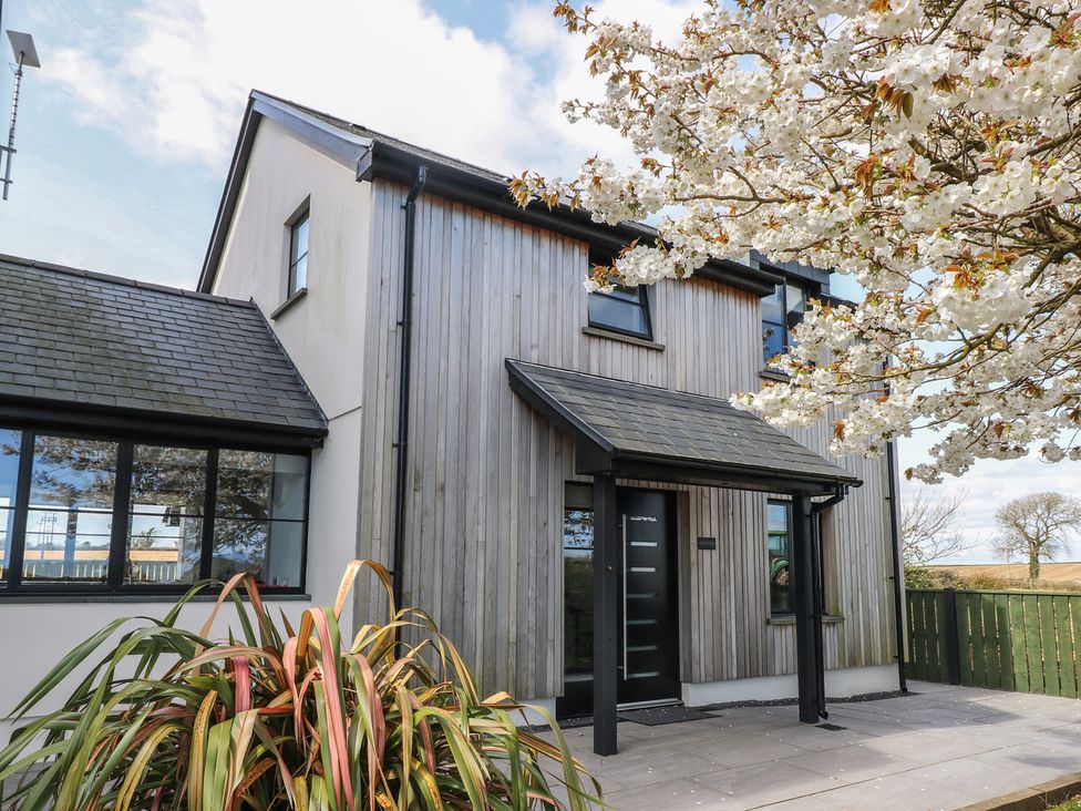 A house with wooden exterior and flowers in front at Just A Cottage St Florence