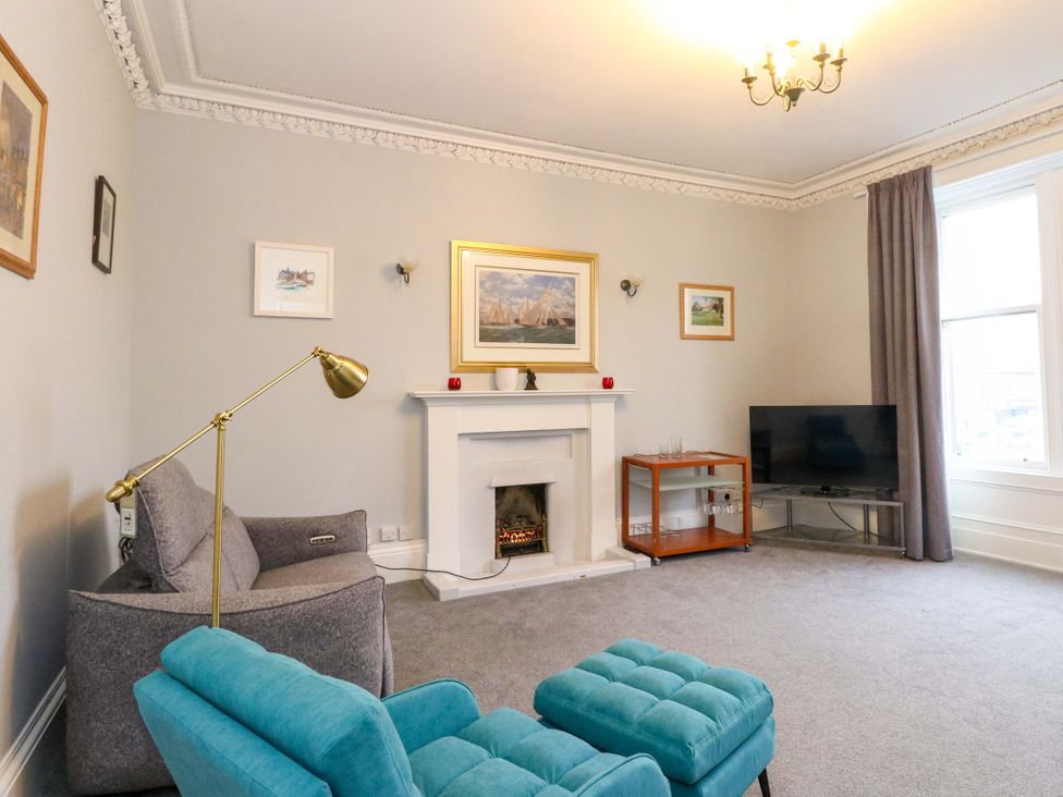 A living room with a sofa, television, and fireplace at 9A Market Square