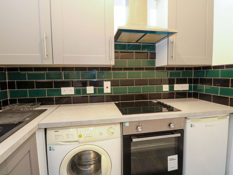 A kitchen with a washing machine, oven, and hob at 9A Market Square