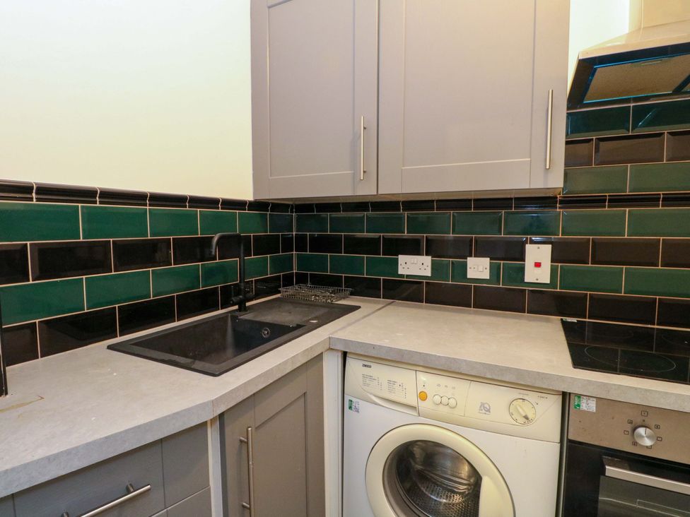 A kitchen with a sink and washing machine at 9A Market Square