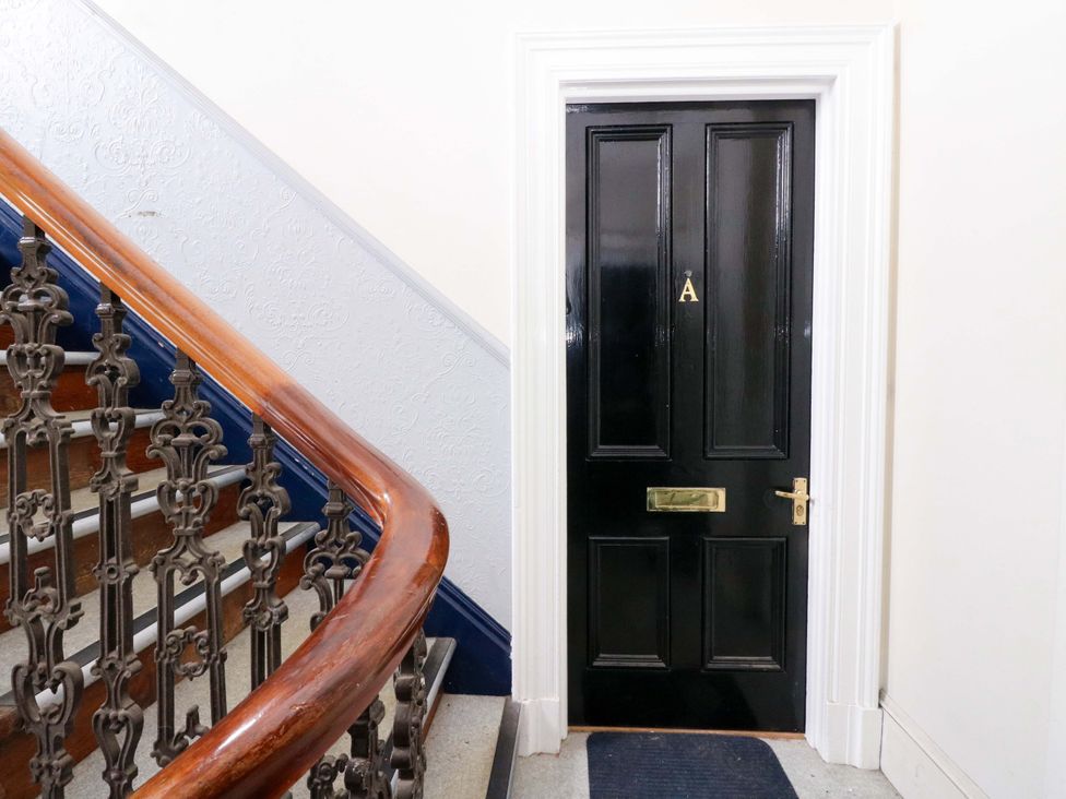 A hallway with a staircase and a black door at 9A Market Square